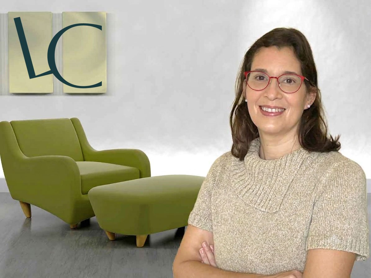 Laura Campista em seu consultório. Divã em tons de verde, parede cinza e quadro decorativo da sua Logo
